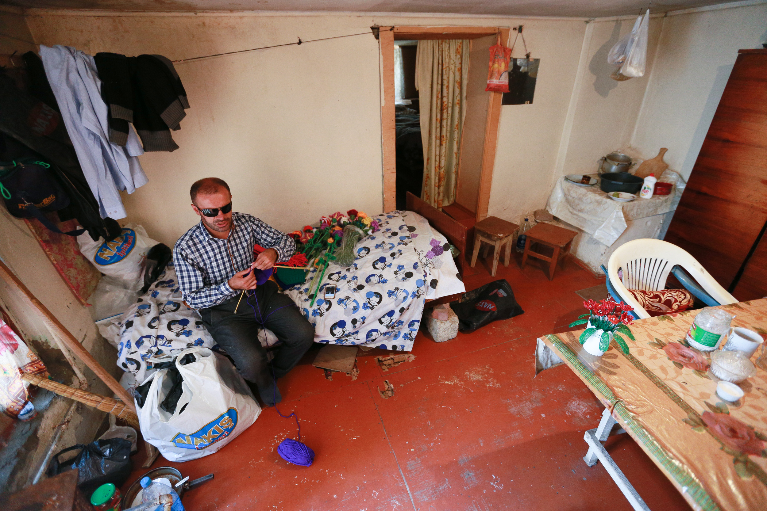 Elchin sitting in his rented apartment and knitting a new hat