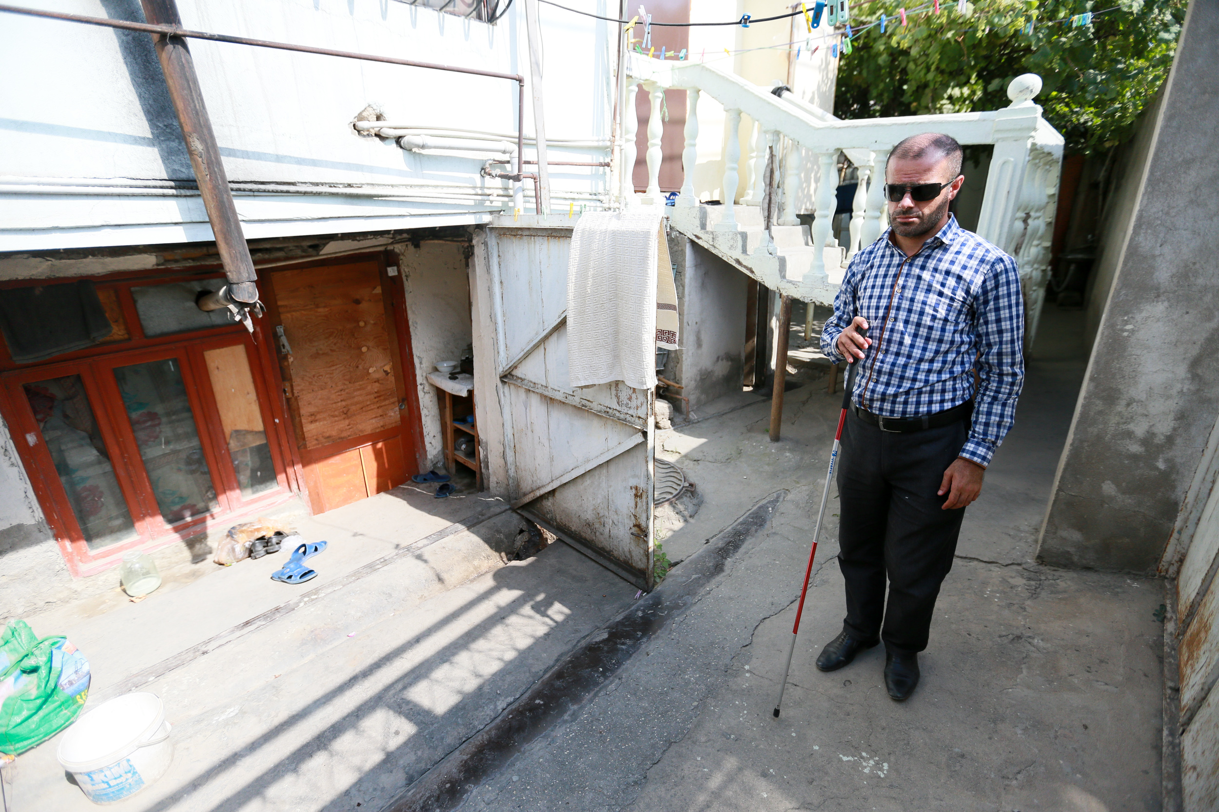Elchin standing in front of his rented house. He says that he pays for his rent with the hats and flowers that he knits
