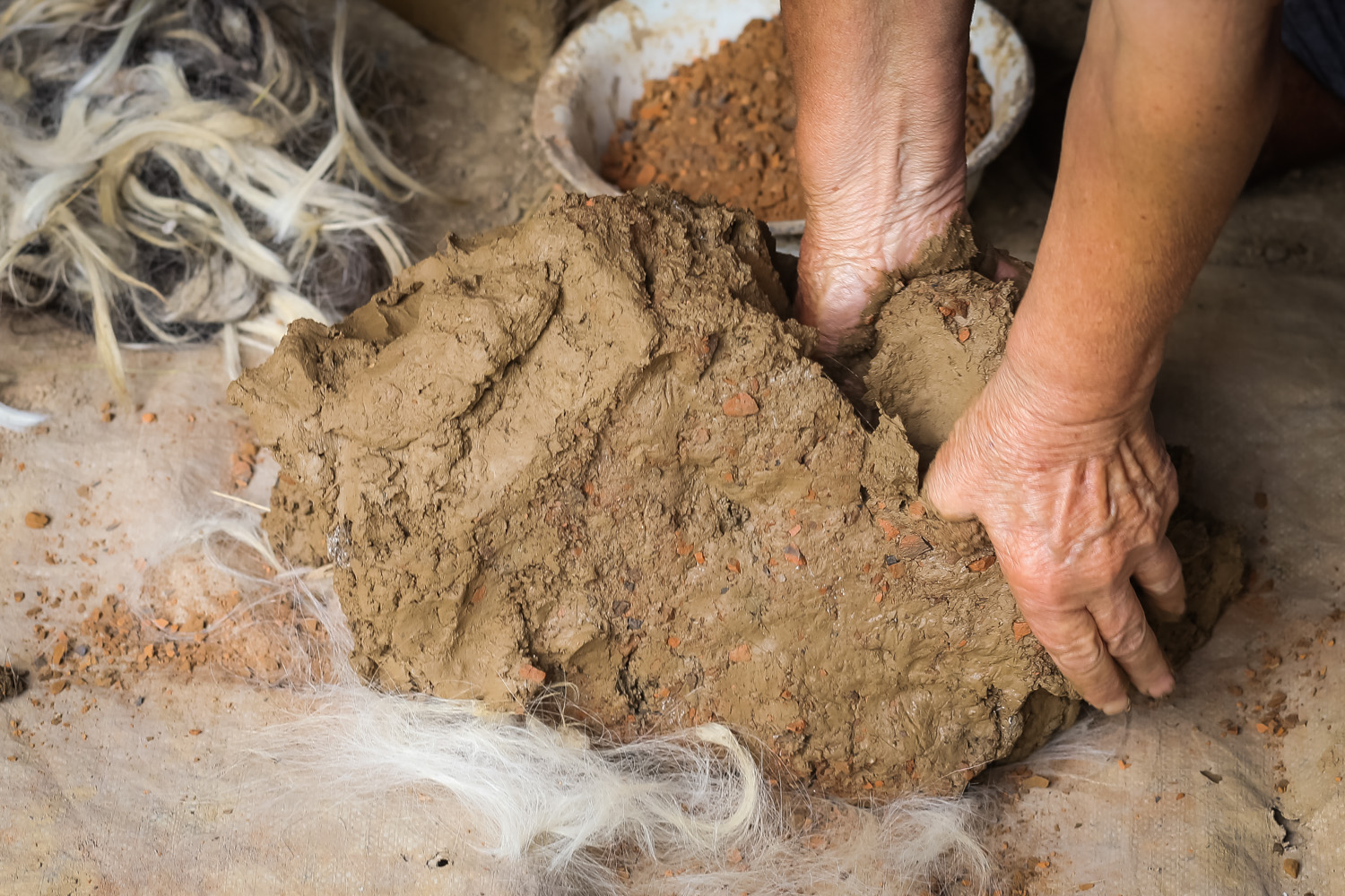 Mixing the mud and clay she will use to make the oven