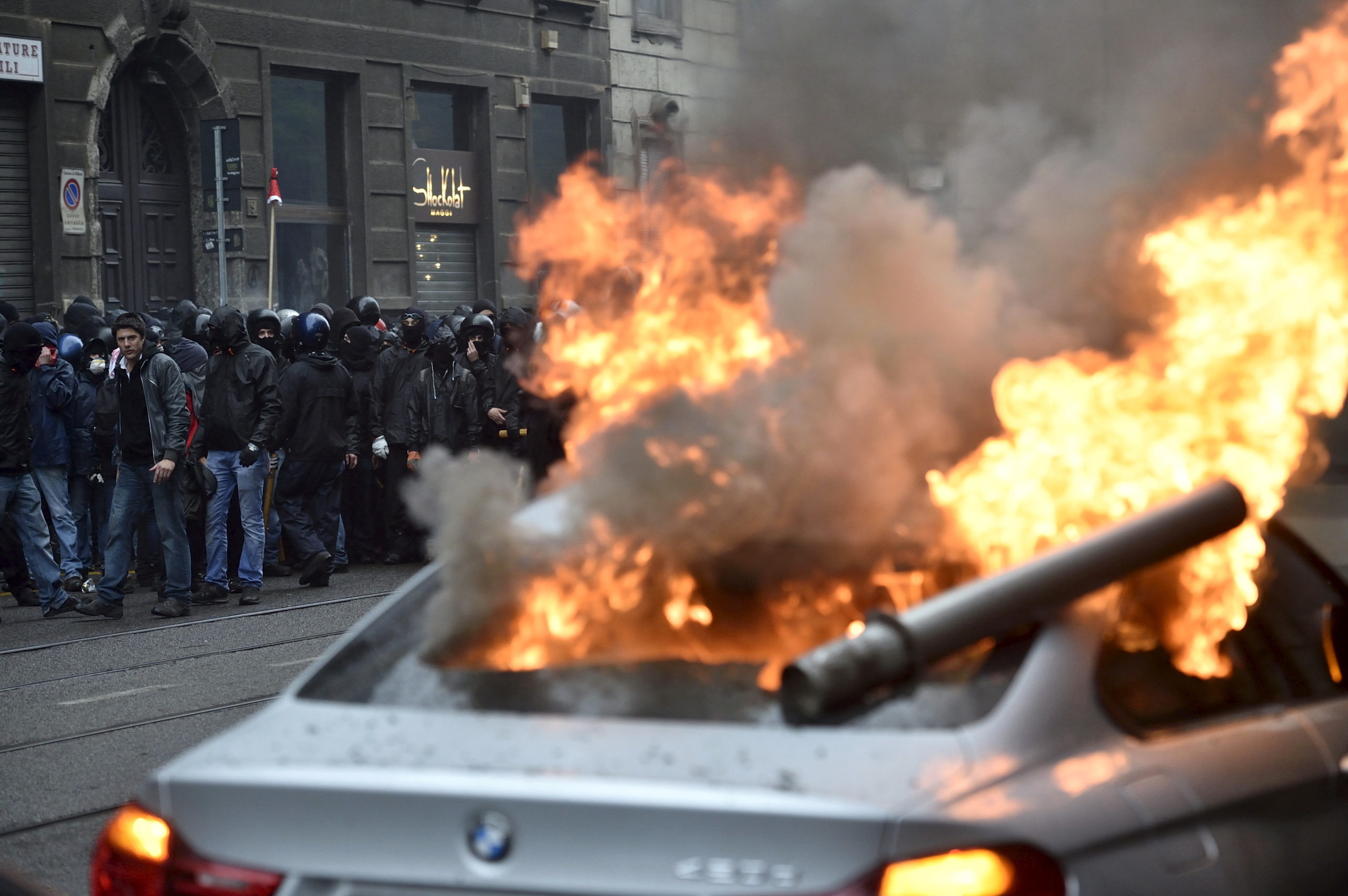 Protesters are seen near a burning car during a rally against Expo 2015 in Milan, Italy, 1 May 2015 (REUTERS/Flavio Lo Scalzo)