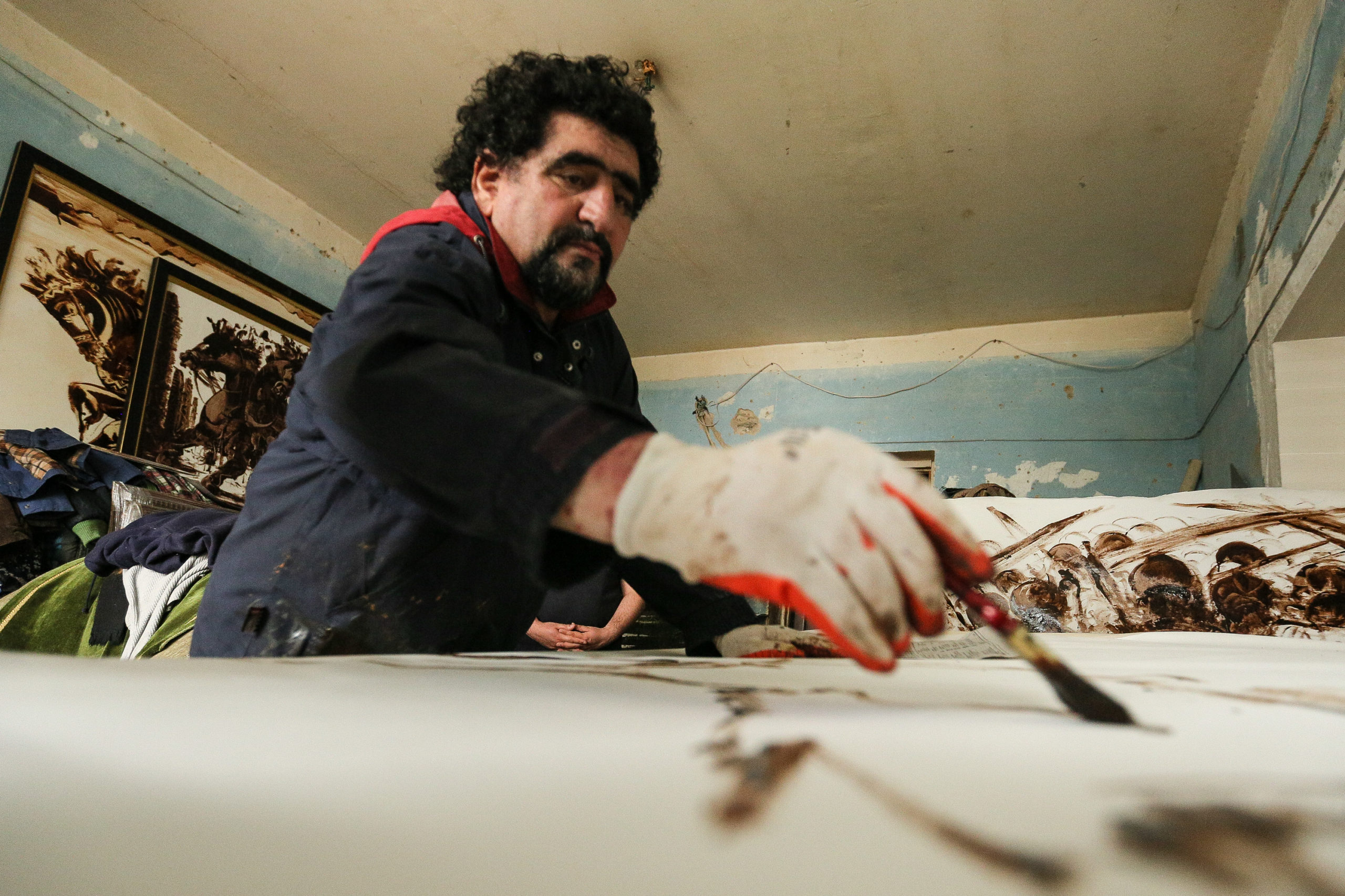 With his hand temporarily injured, Sabir Chopurov paints by brush.