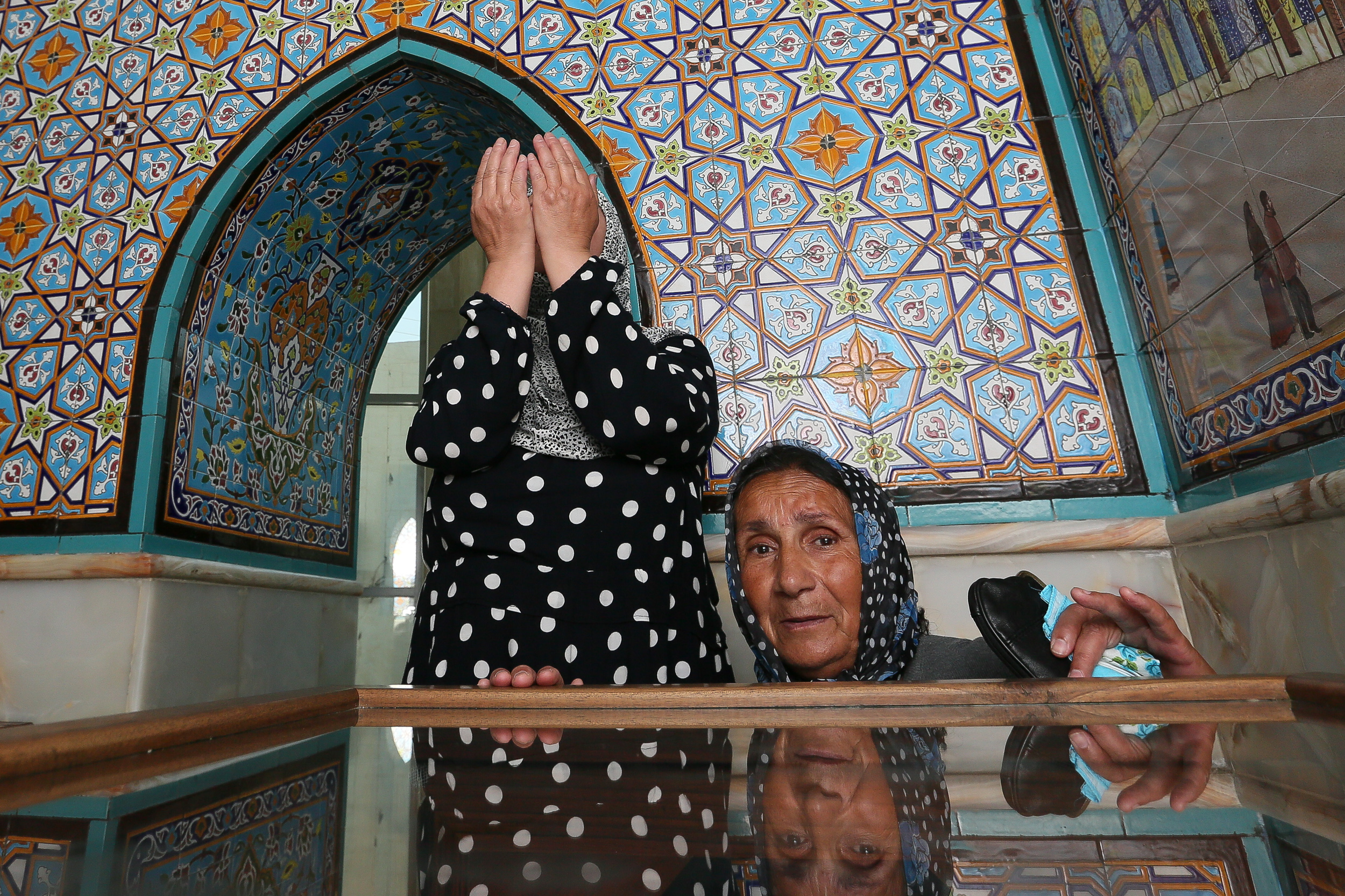 Ziyarətə gəlmiş iki qadın dua edərək, çətinlikdə olan işlərinin tezliklə düzəlməsini istəyir