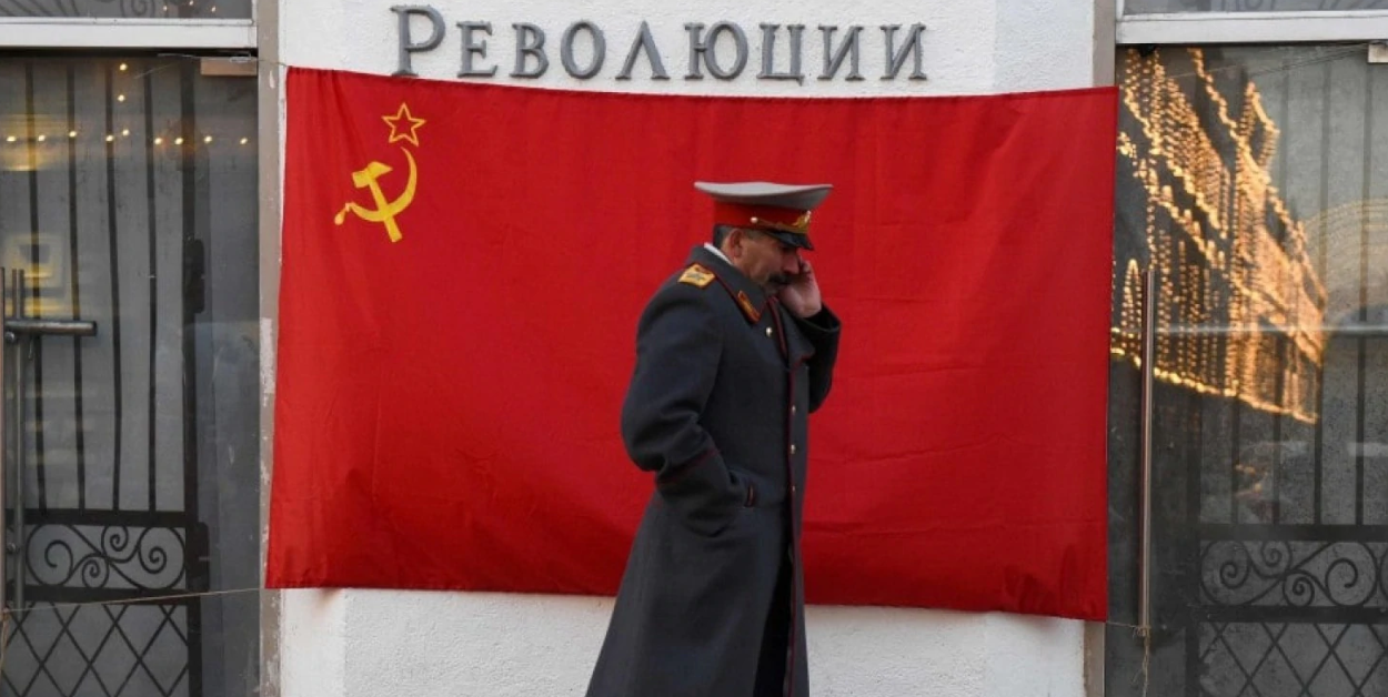 Stalinə oxşadılmış adam Sovet bayrağının qarşısında