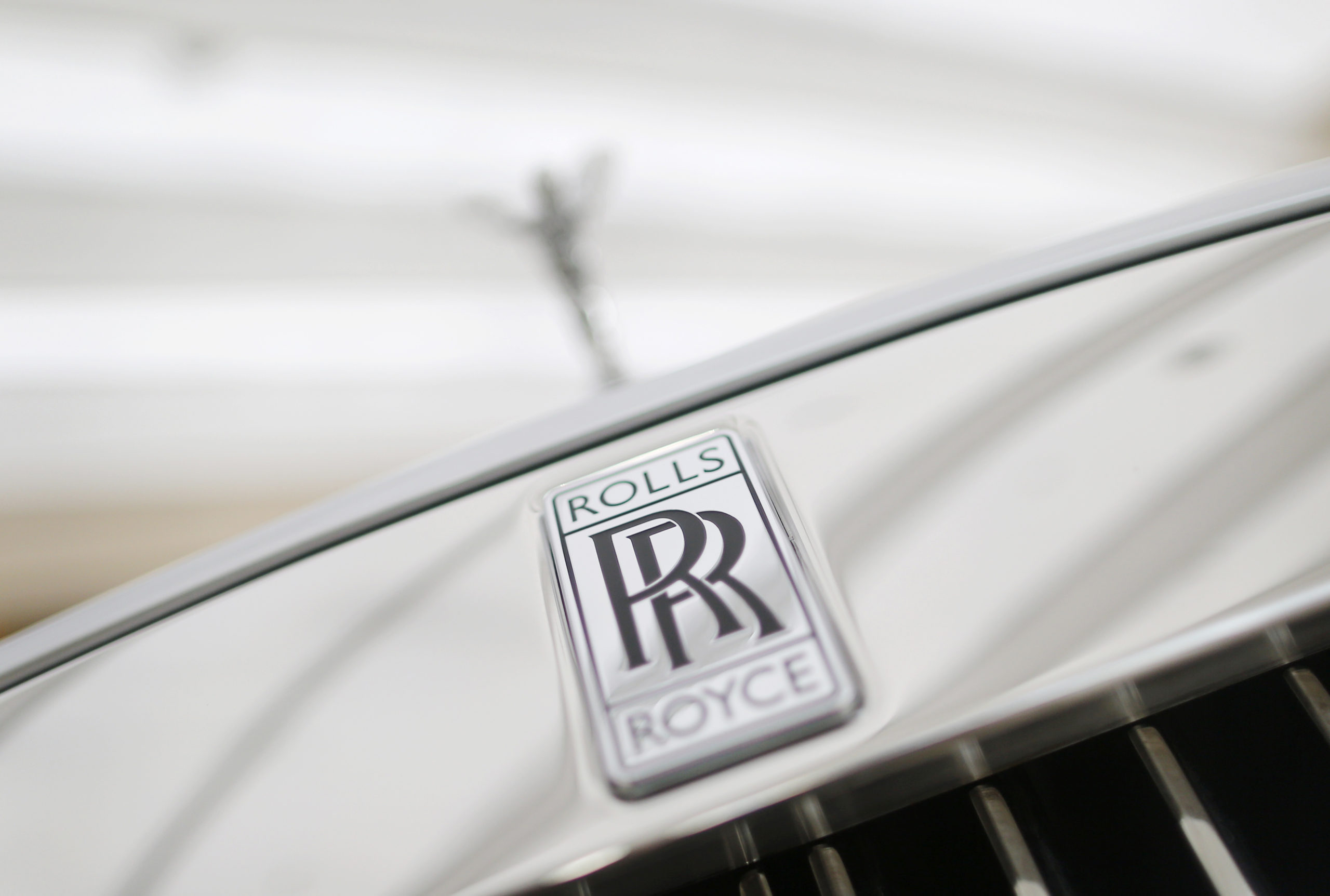 A Rolls-Royce mascot known as 'Spirit of Ecstasy' stands above the brand's logo on the front of a Rolls-Royce Ghost in a showroom in Singapore October 8, 2013.