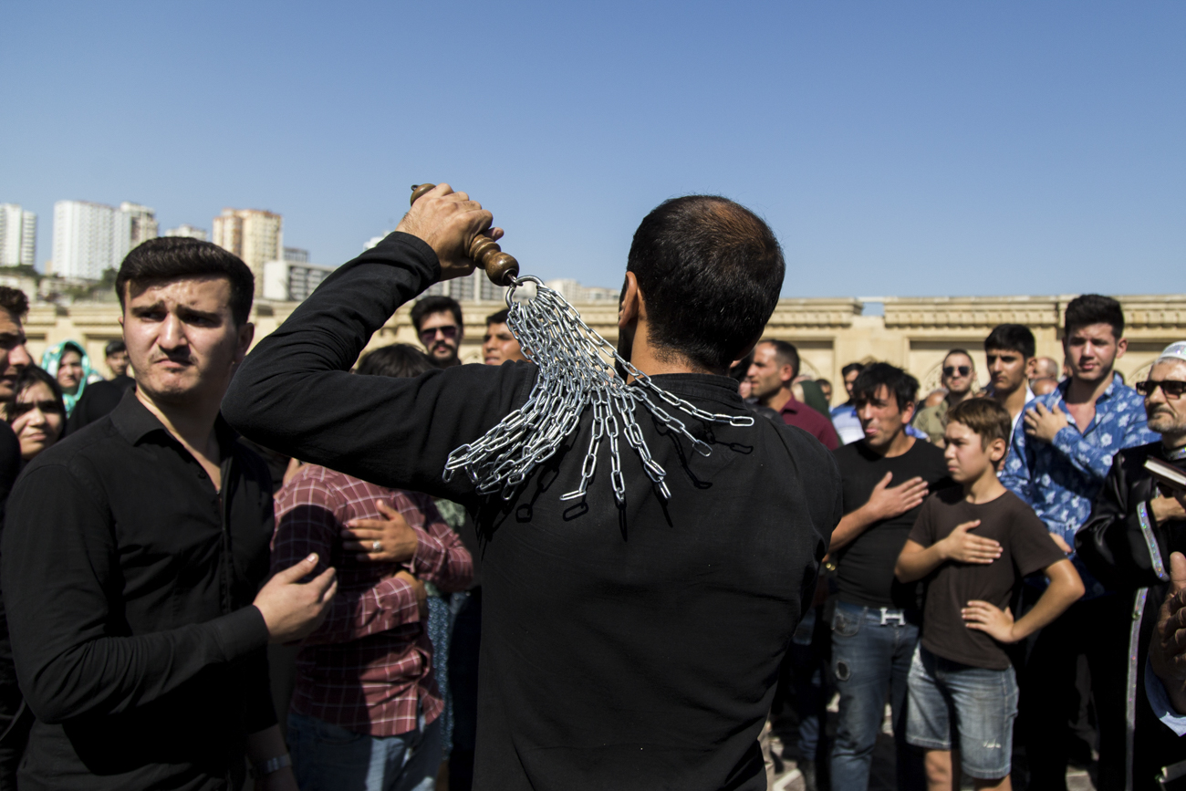 A man beats himself with chains in the square outside the mosque. (Ehtiram Jabi / Eurasianet)