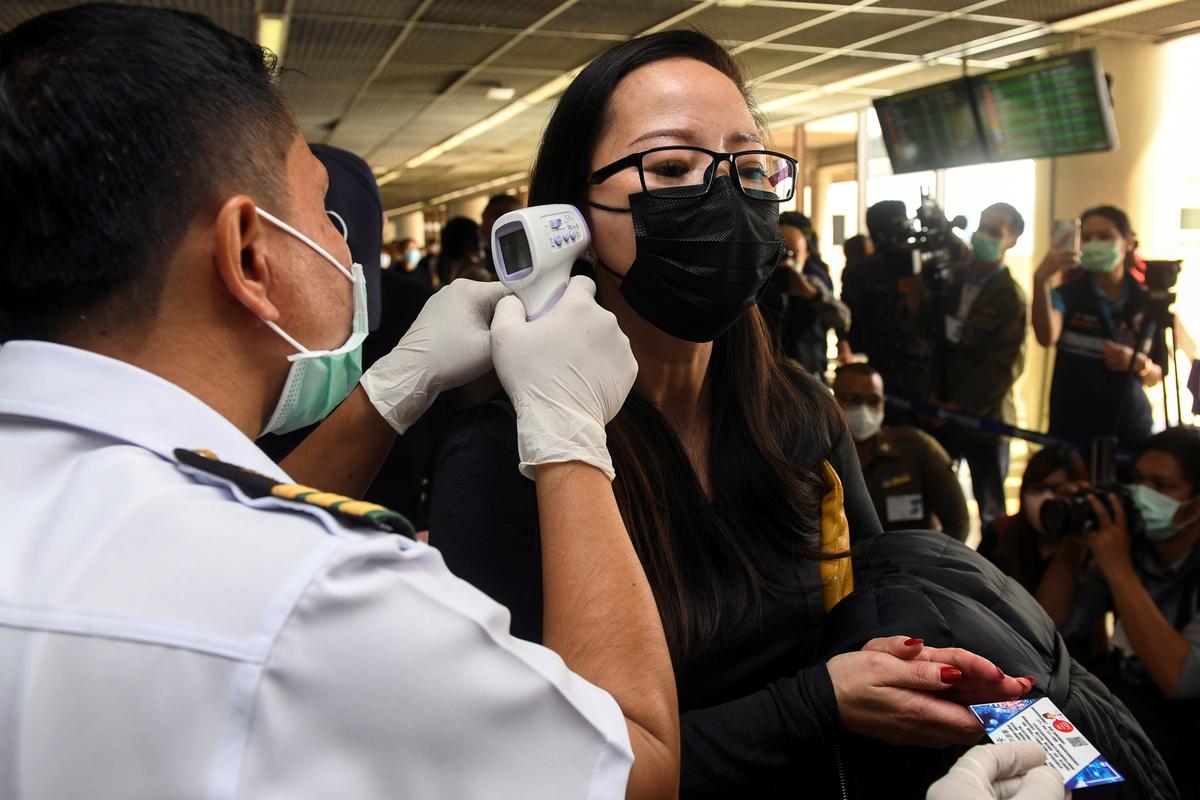 A health worker uses an infrared thermometer to check the temperature of a tourist who arrives at Bangkok's Don Mueang Airport, Thailand, 25 January, 2020